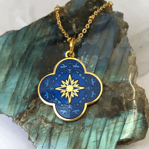 A blue flower shaped pendant on a gold chain.